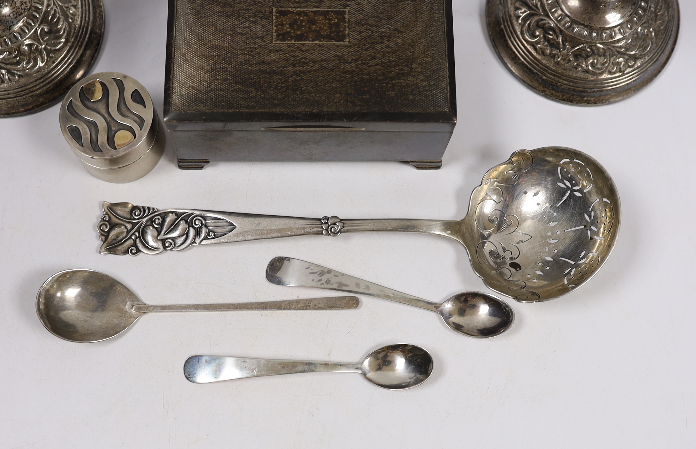 Sundry silver including a cigarette box, pair of dwarf candlesticks, modern silver circular pill box and three spoons, maker GR and a large early 20th century stylish Swedish white metal sifter ladle.